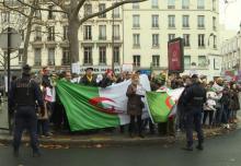 Capture d'écran d'une vidéo AFPTV montrant des manifestants brandissant des drapeaux algériens près du consulat d'Algérie à Paris alors que débute la procédure de vote à l'élection présidentielle pour