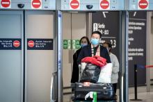 Une employée aide des voyageurs en provenance de Chine le 26 janvier 2020 à l'aéroport de Roissy