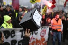 Un homme tient une caisse pour soutenir les grévistes, dans une manifestation à Paris le 26 décembre 2019