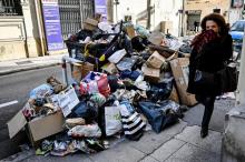 Une passante près d'un empilement d'ordures non ramassées en raison d'une grève des éboueurs, à Marseille le 3 février 2020