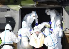Des équipes médicales transportent un patient contaminé par le Covid-19 pour l'évacuer à bord d'un hélicoptère vers l'hôpital d'Essen, en Allemagne, le 28 mars 2020 sur le parking du CHR de Metz