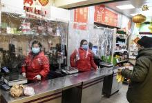 Des caissières travaillent derrière des rideaux en plastique installés à la caisse d'une épicerie chinoise à Paris, le 24 mars 2020
