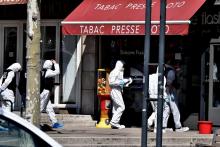 Des policiers en combinaison de protection entrent dans un tabac presse, le 4 avril 2020 à Romans-sur-Isère après une attaque au couteau