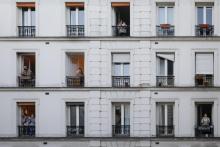 Des personnes à la fenêtre de leurs appartements applaudissent les personnels soignants, le 30 mars 2020 à Paris pendant confinement instauré en France