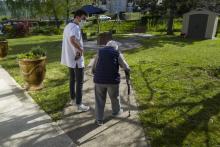 Un soignant de l'Ehpad Korian Vill'Alize à Thises avec un résident dans le jardin de la maison de retraite, le 16 avril 2020