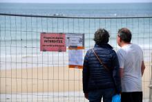 Un couple devant des pancartes épinglées sur une clôture bloquant l'accès à la plage de Saint-Malo, le 04 mars 2020