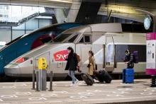 Des voyageurs masqués passent à côté d'un TGV à la gare Montparnasse, le 12 mai 2020 à Paris