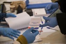 Un assesseur muni de gants de protection contre le nouveau coronavirus vérifie une carte électorale, le 15 mars 2020 dans un bureau de vote de Mulhouse