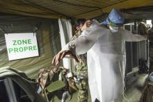 Une militaire aide un collègue à enfiler une blouse de protection sans la contaminer, le 24 mars 2020 à l'hôpital de campagne destiné à accueillir les malades du Covid-19, à Mulhouse