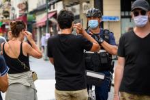 Un policier municipal demande à des passants de porter un masque de protection, le 15 août 2020 à Paris
