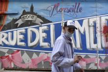Un homme portant un masque devant un graffiti à Marseille, France, le 14 septembre 2020