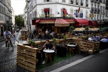 Des personnes prennent un verre à la terrasse élargie d'un bar à Paris, le 23 juillet 2020