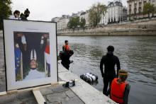 Des membres d'Action Climat Paris, qui avaient décroché des portraits d'Emmanuel Macron dans les mairies s'apprêtent à les poser sur la Seine à Paris le 15 octobre 2020