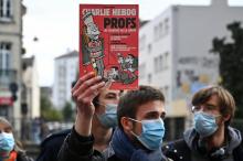 Un homme brandit un numéro de Charlie Hebdo consacré à l'enseignement sur la laïcité lors d'un rassemblement à Rennes le 17 octobre 2020 en hommage au professeur tué la veille dans les Yvelines