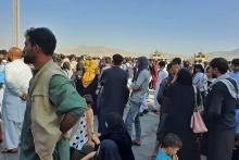 Des Afghans attendent sur le tarmac de l'aéroport de Kaboul de pouvoir quitter le pays tombé aux mains des talibans, le 16 août 2021