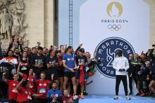Des amateurs anonymes posent aux côtés du recordman du monde du marathon Eliud Kipchoge après avoir participé au Marathon Pour Tous, épreuve de 5 km qualificative pour les Jeux de 2024, le 31 octobre 