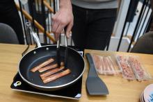 Des tranches de succédané végétal de bacon cuisent dans une poêle au siège de La Vie, jeune pousse française de substitut à la viande, le 7 janvier 2022 à Paris