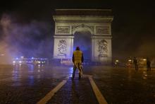Un manifestant portant un gilet jaune (Gilet jaune) se tient devant l'Arc de Triomphe sur l'avenue des Champs Elysées à Paris lors d'une manifestation des Gilets jaunes contre la hausse des prix du pé