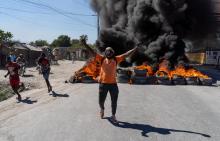 Un homme crie devant une barricade en feu pendant une manifestation de policiers à Port-au-Prince,