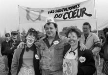 Coluche pose devant l'entrée d'un des trois bâtiments des "Restos du Coeur" à Paris en décembre 1985.