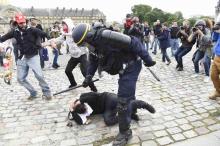 Un policier maîtrise un manifestant, en marge du défilé du 14 juin