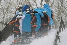 Des pompiers transportent un survivant d'une avalanche, le 27 mars 2017 dans la ville de Nasu, au no