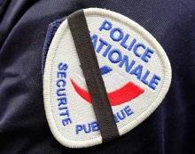 Un ruban noir sur l'insigne d'un policier en hommage à deux collègues tués en service, le 26 février