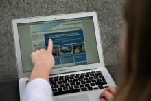 Une femme montre le site Web du NHS (East and North Hertfordshire), informant les utilisateurs d'un 