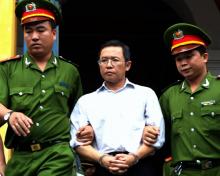 Le blogueur dissident franco-vietnamien Pham Minh Hoang (c) escorté par des policiers à la sortie du