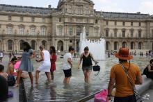 People cool off in a fountain pool near The Louvre Museum in Paris on June 21, 2017, as temperatures
