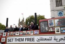 Un bus rouge à impériale circulant dans Londres, couvert de portraits de Syriens emprisonnés ou disp