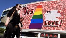 Des personnes passent devant un immense panneau d'affichage pour le "oui" au mariage gay à Sydney le