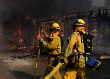 Des pompiers tentent de sauver des flammes les maisons menacées par un important incendie dans le co