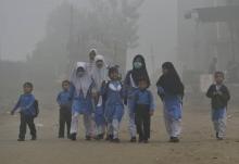 Photo prise le 6 novembre d'enfants pakistanais se rendant à l'école sous un épais brouillard de smo