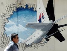 Photo d'archives prise le 8 mars 2016 montrant un homme à Shah Alam en Malaisie marchant devant une fresque murale de l'avion disparu du vol MH370 de Malaysia Airlines