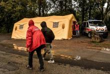 Des migrants passent devant une tente de la Protection civile, le 5 octobre 2017 à Grande-Synthe, da