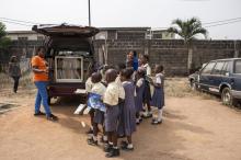 Funmi Ilori (g), devant sa camionnette d'I-Read, explique à des élèves de l'école primaire Bethel l'importance de lire, le 30 janvier 2018 à Lagos, au Nigeria