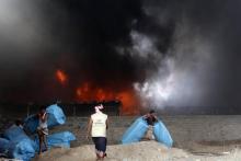 Des travailleurs tentent de sauver des flammes des sacs d'aide alimentaire dans un dépôt du Programme alimentaire mondial (PAM) dans le port yéménite de Hodeida, sur la mer Rouge, le 31 mars 2018