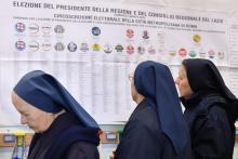 Des bonnes soeurs regardent les listes électorales dans un bureau de vote à Rome, le 4 mars 2018