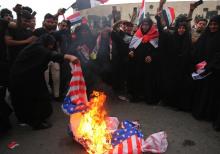 Des manifestants irakiens brûlent des drapeaux américains à Bagdad lors d'une protestation contre les frappes occidentales en Syrie voisine, le 15 avril 2018