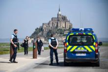 People stand on the road leading to the Mont-Saint-Michel as Gendarmes block the access after it was evacuated on April 22, 2018 of its tourists and residents "as a precautious measure" after an unide
