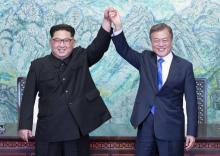 Le président sud-coréen Moon Jae-in (d) et le leader nord-coréen Kim Jong Un lèvent leurs mains unies pendant le sommet intercoréen, le 27 avril 2018 à Panmunjom