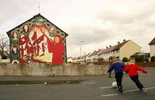 Des enfants jouent au football le 14 février 2006 près d'une fresque murale dans un quartier républicain de Belfast en Irlande du Nord