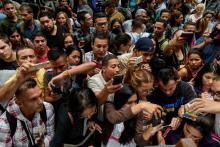 Des Vénézuéliens prennent en photo la liste des documents à fournir pour obtenir un visa spécial du consulat du Chili, le 16 avril 2018 à Caracas