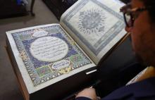 L'Afghan Mohammad Tamim Sahibzada, maître ès miniatures et responsable des enluminures, montre un Coran en soie dans les 610 pages ont été peintes à la main, le 19 avril 2018 à la Fondation britanniqu