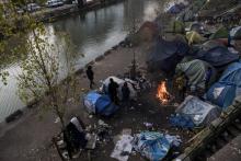 Des migrants, la plupart Afghans, se réchauffent autour d'un feu le 23 février 2018 à Paris où un froid sibérien est attendu