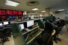 Des opérateurs iraniens surveillent les marchés financiers à la Bourse de Téhéran le 8 mai 2018