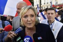 La présidente du Front national Marine Le Pen répond aux journalistes lors d'une manifestation contre la politique du gouvernement en matière d'immigration le 20 avril 2018 à Paris
