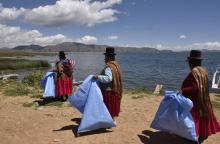 Des femmes indigènes aymaras nettoient les déchets sur les bords du lac Titicaca à Puerto Perez, en Bolivie, le 18 avril 2018