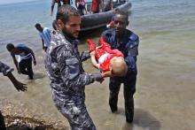 Le corps d'un des trois bénés repêchés vendredi après le naufrage d'une embarcation est porté par des membres des forces de sécurité libyennes, le 29 juin 2018 à al-Hmidiya